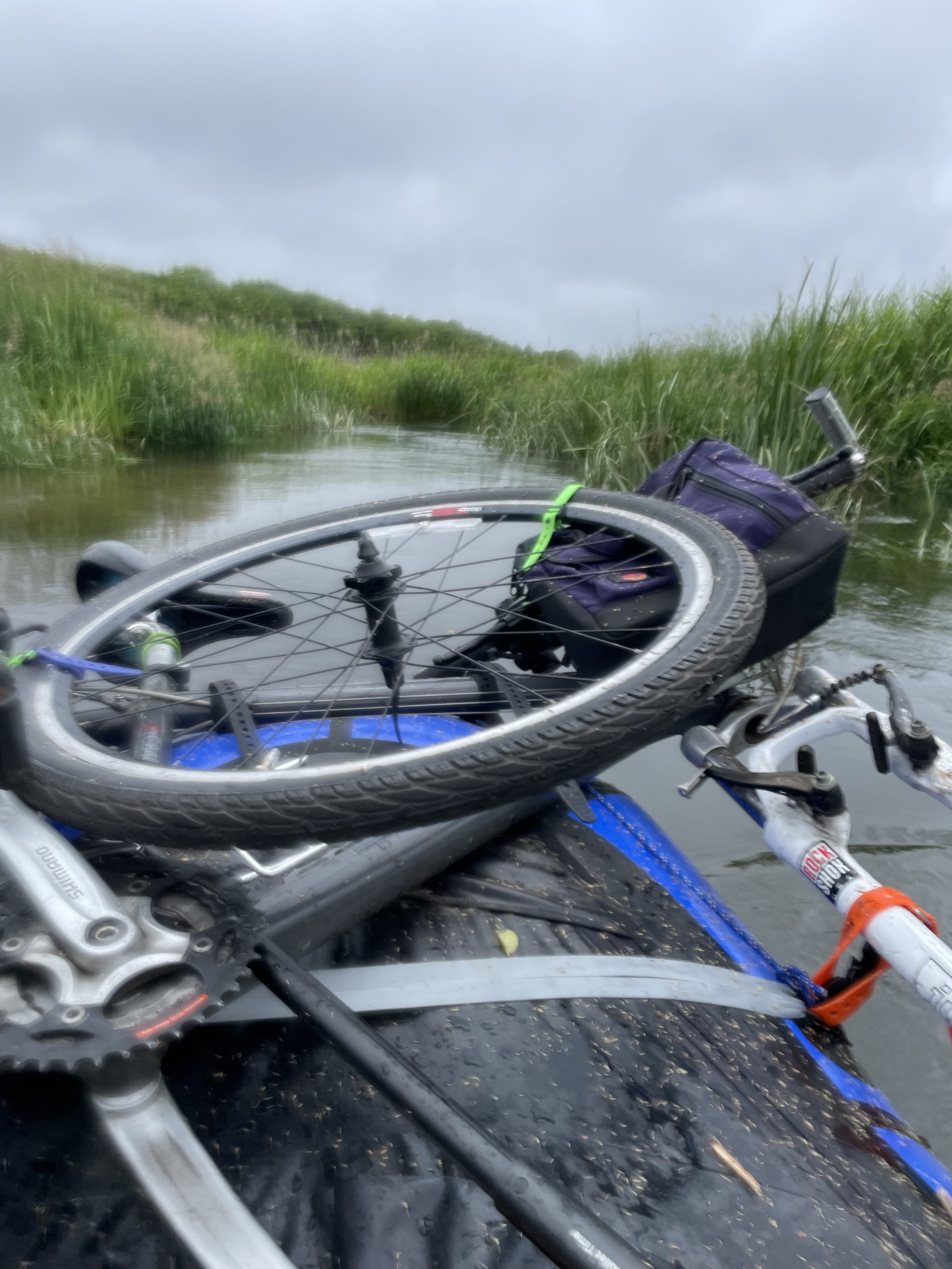A gap in the grass opens onto grey sky over still water